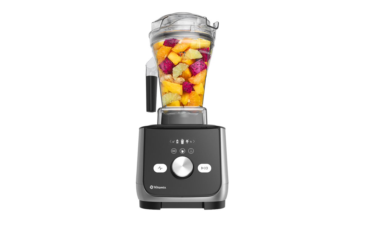 A Ascent X5 Vitamix blender filled with fruit in a clear container. Black and silver base with a silver dial in the middle.