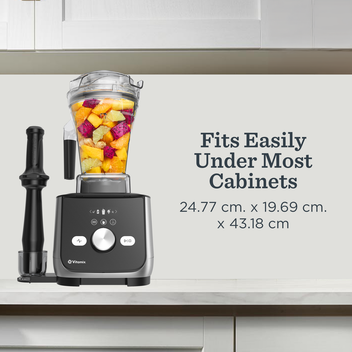 Vitamix Ascent X blender with Tamper in holder and a clear container filled with fruit and vegetables sits on a kitchen countertop. Text on the right reads 'Fits Easily Under Most Cabinets' with dimensions below.
